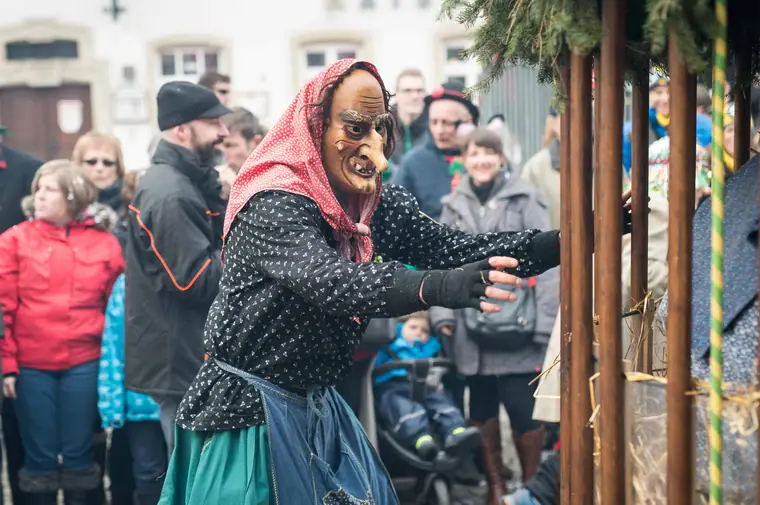 Hexe mit rotem Kopftuch zwischen Zuschauern
