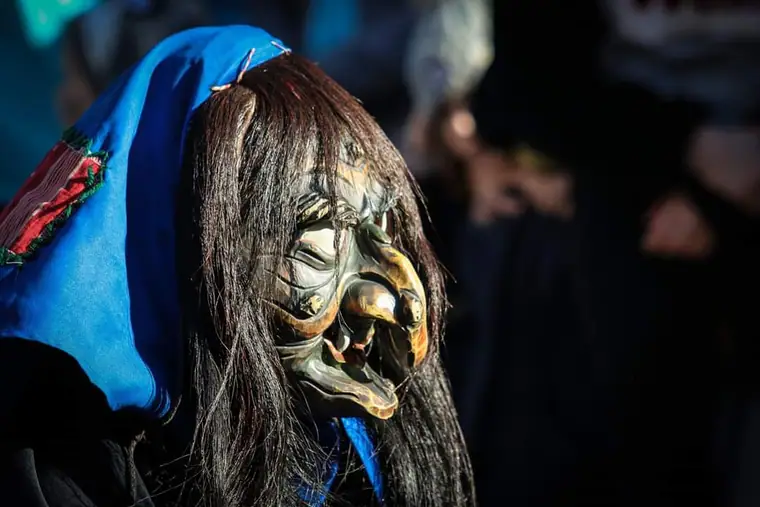 Holzmaske einer Krum-Hexe mit blauem Kopftuch