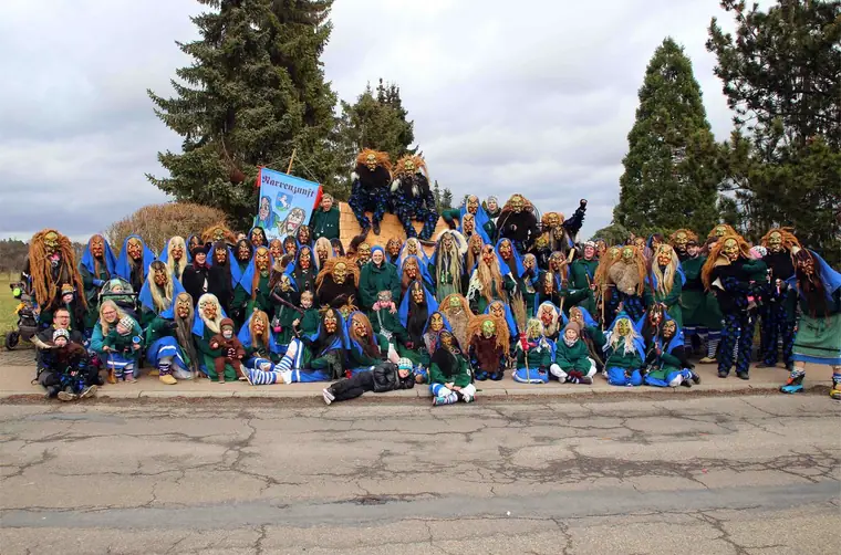 Gruppenbild der Narrenzunft mit Glammhoaga Hexa und Schnoagabeisern vor dem Zunftbanner