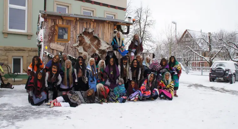 Gruppenbild der Zunft im Schnee vor dem Hexenwagen